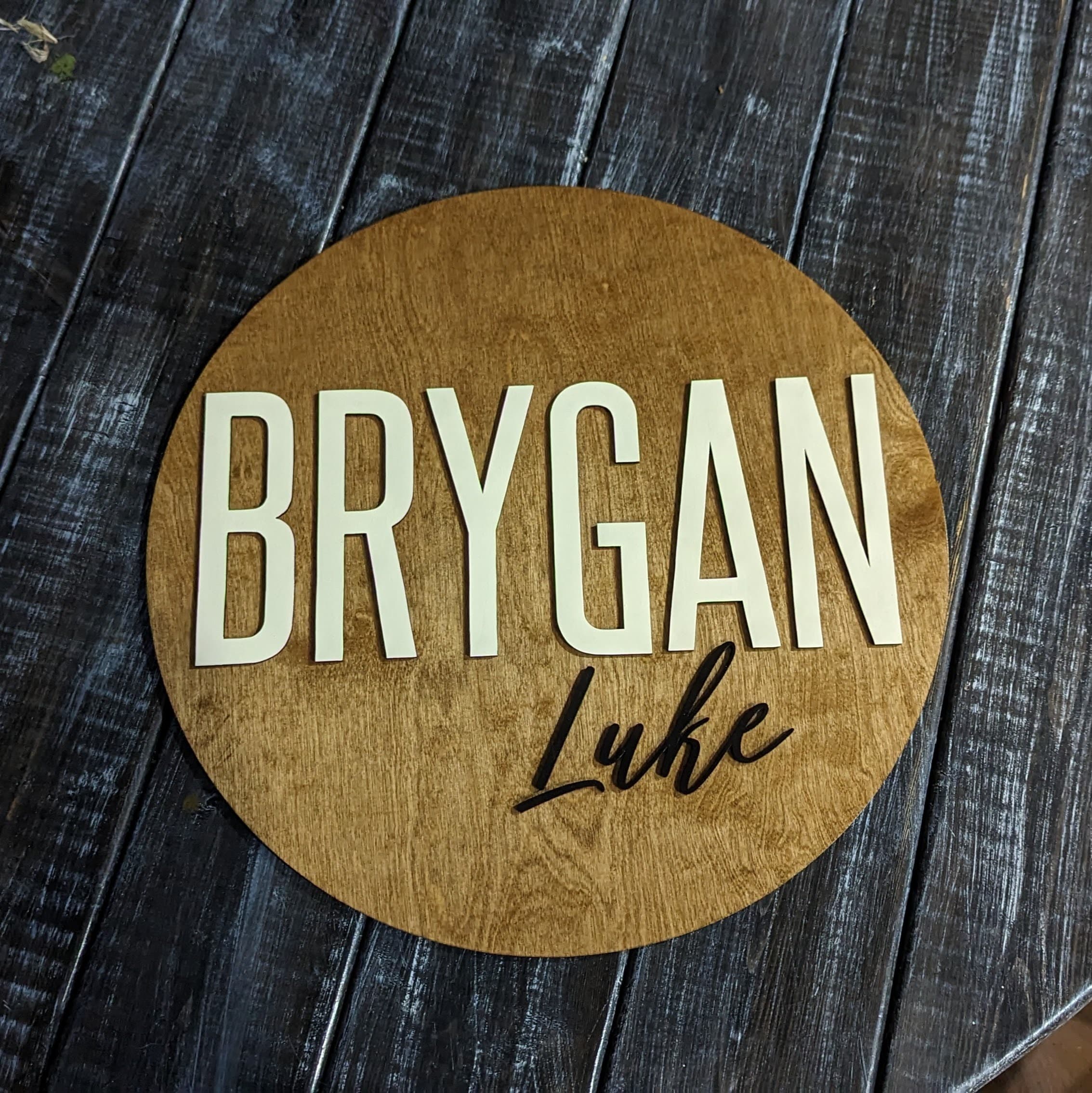 Round baby name sign with dimensional lettering and floral accents