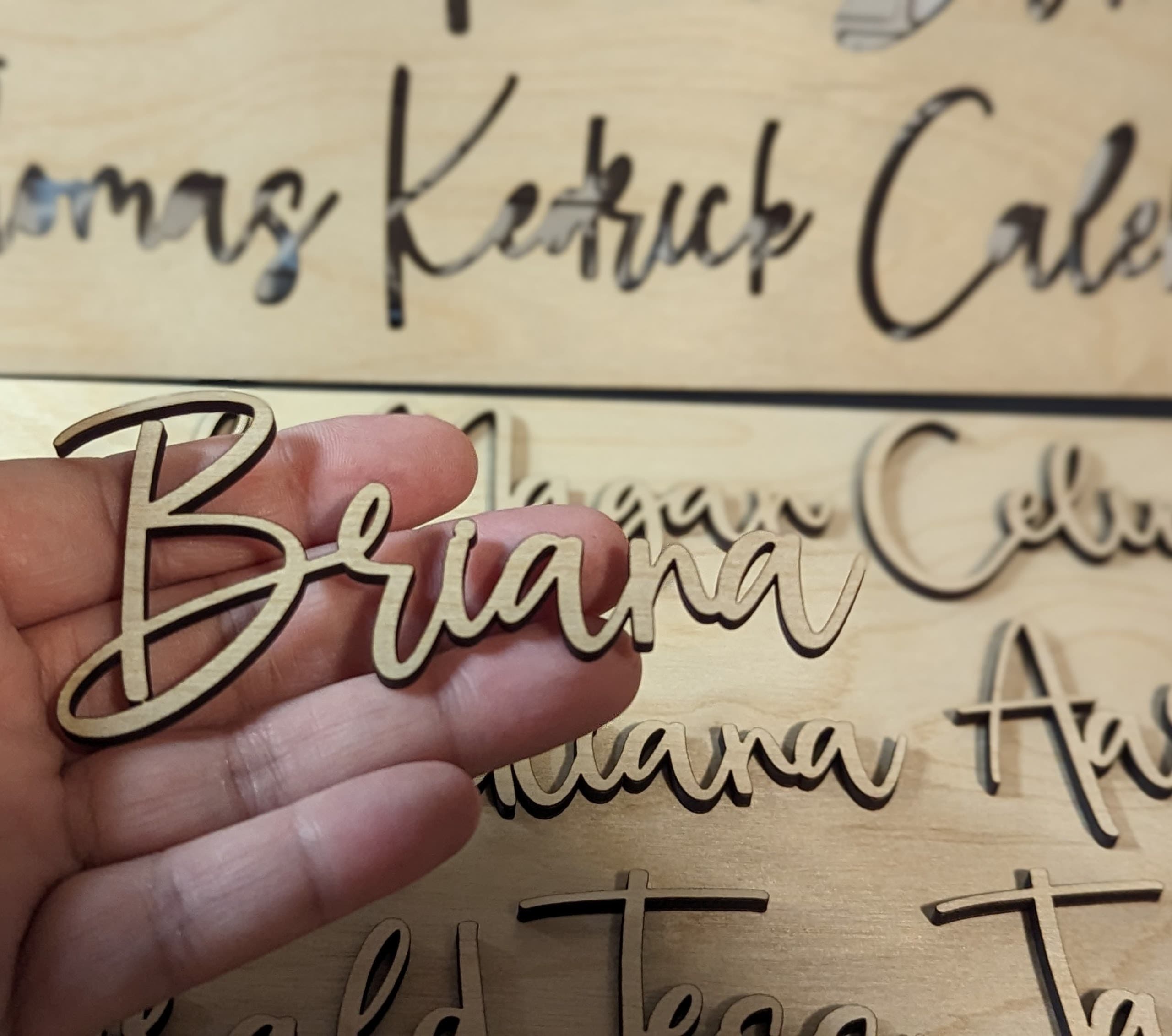 Hand placing raised script lettering onto a personalized board